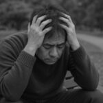 新しい職場が辛くて頭を抱える男性の姿